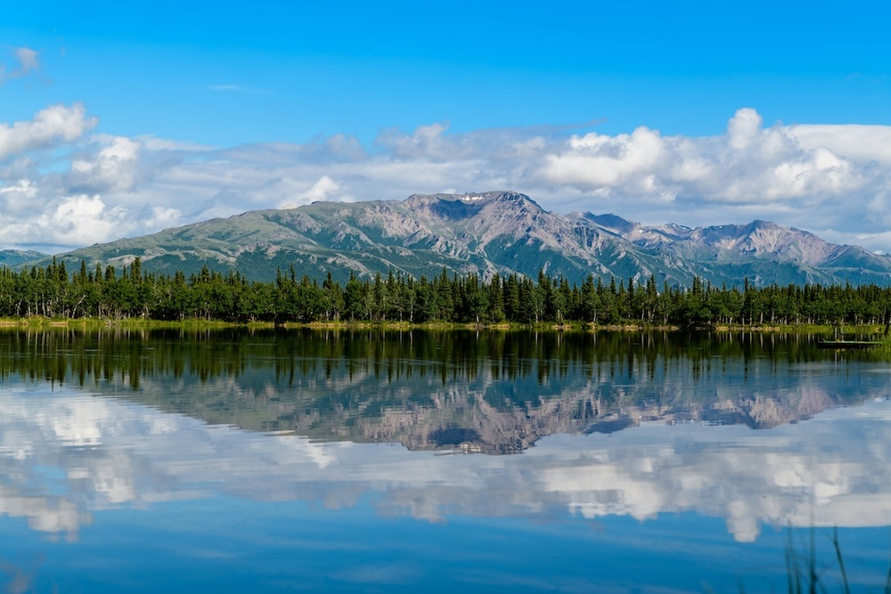 Mountain reflected in a still lake under a blue sky.