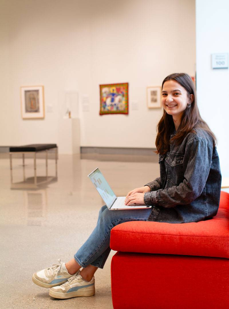 Hope College Intern, Jenna, working on her laptop in the gallery