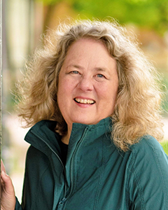 Blonde, curly haired woman with green coat, smiling