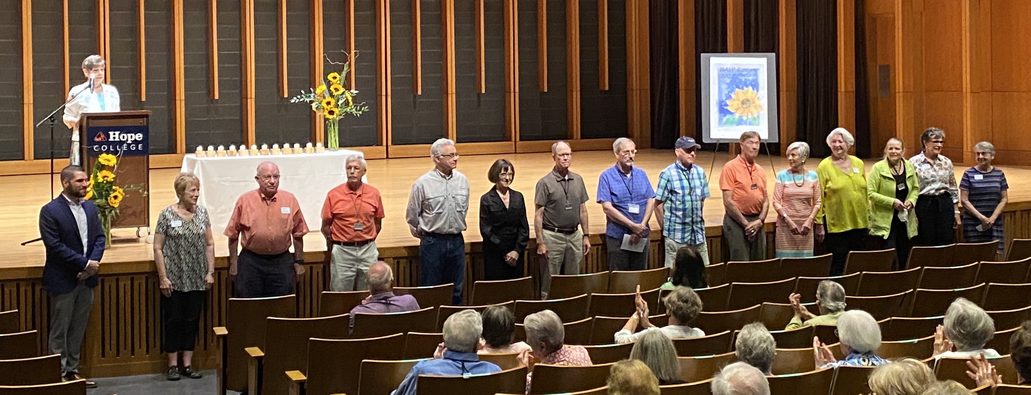HASP 2022–2023 Board of Directors The 15 board of directors standing in front of a stage while a presenter speaks.